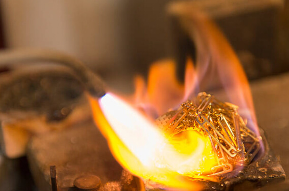 Photo d'une flamme de chalumeau en train de fondre des vieux bijoux pour recycler son or.